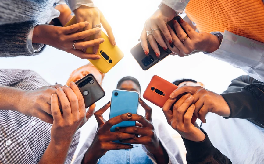 Five people standing in a circle looking at their phones