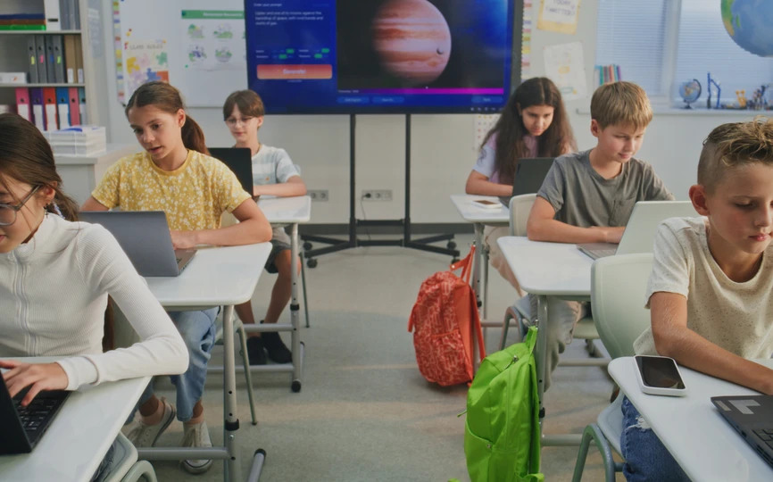 Six elementary school students at their own desks typing on a laptop computer