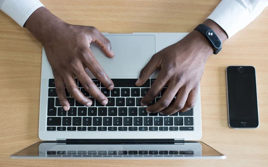 Hands type on a laptop keyboard