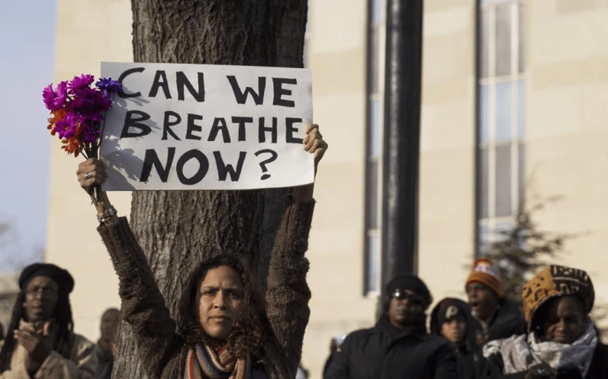 Person holding up a sign that says "Can we breathe now?"
