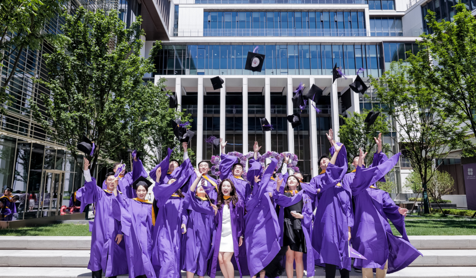 Students celebrate in graduation attire by throwing their caps in the air during NYU Shanghai’s Master’s Convocation.