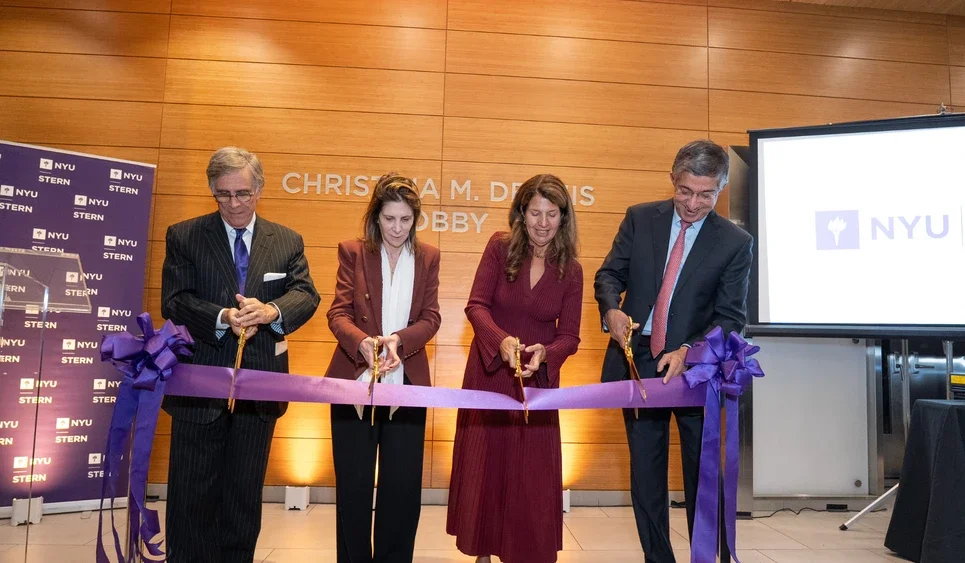 Four people use scissors to cut a large violet ribbon