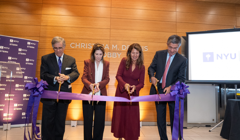 Four people use scissors to cut a large violet ribbon