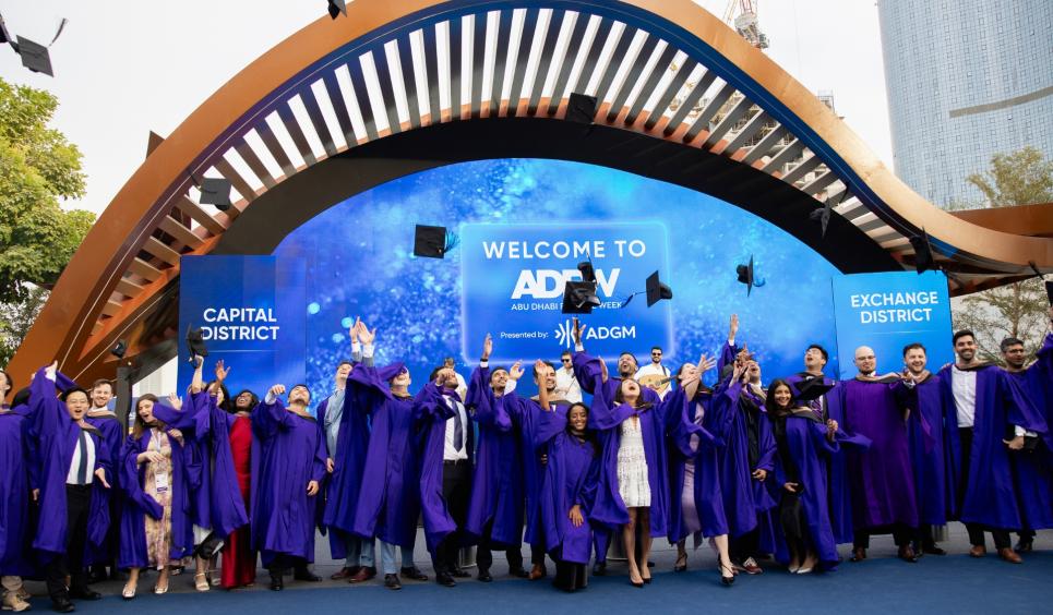 Stern at NYU AD students dressed in graduation gowns throw their caps into the air