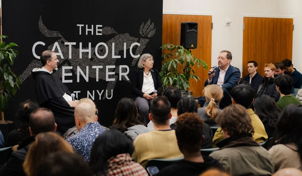 Father Cassian, Manuela and Foster speak in a packed room