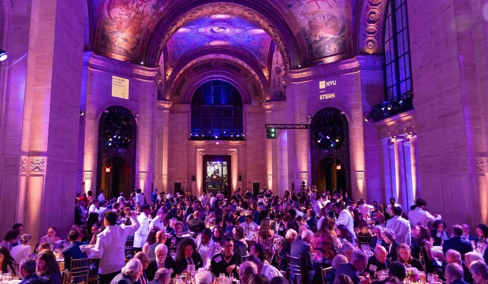 A room lit in violet with tables filled with people