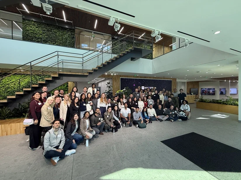 A group of students poses for a photo in front of a staircase in the C3.AI office