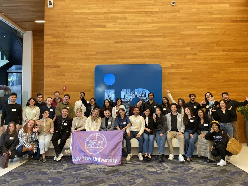 Students pose in front of a LinkedIn logo holding an NYU banner