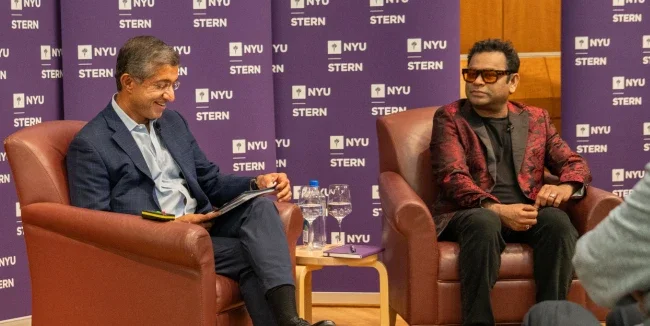 Dean Anand and A R Rahman sitting in chairs in conversation in front of an audience