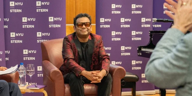 A R Rahman sitting in a chair 