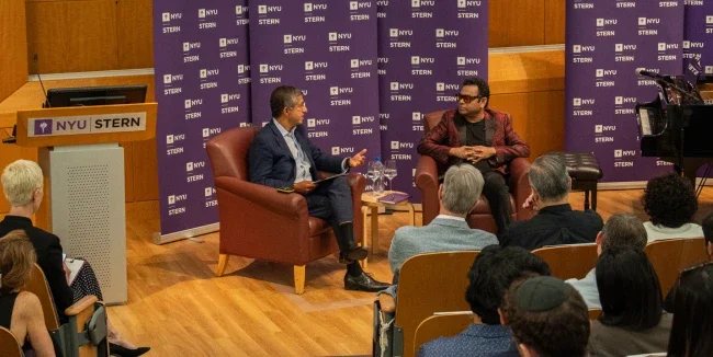 Dean Anand and A R Rahman sitting in chairs in conversation in front of an audience