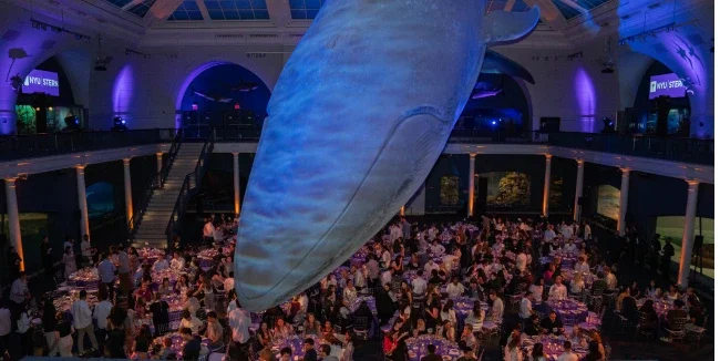 MBA students sit at tables underneath a large blue whale model