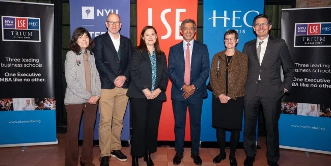 Six members of TRIUM leadership stand in front of banners with the TRIUM logo and logos from NYU Stern, LSE and HEC