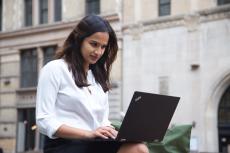 Student sits outside and works on a laptop